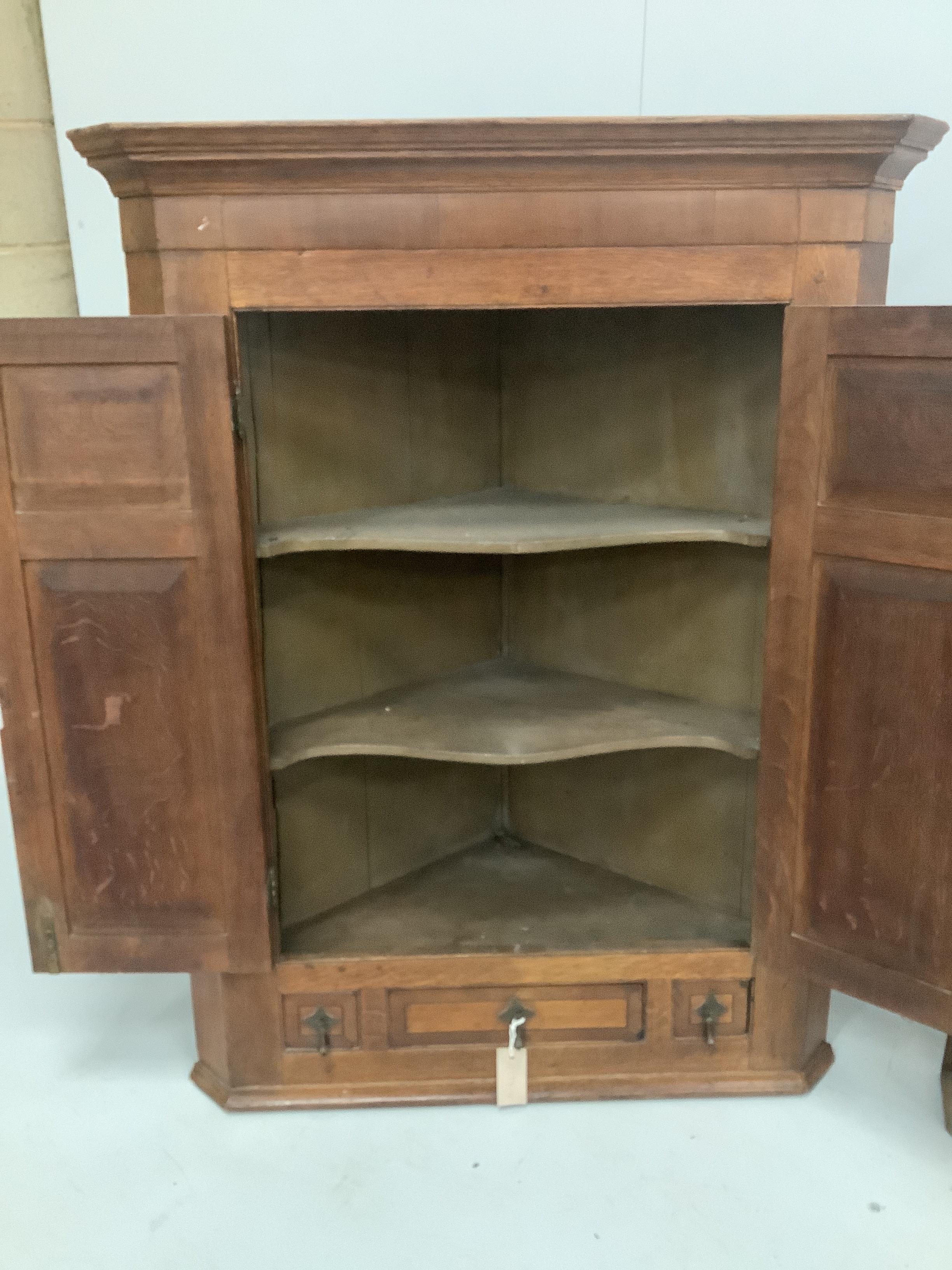 A George III inlaid oak hanging corner cupboard, width 87cm and a similar plainer example, width 62cm